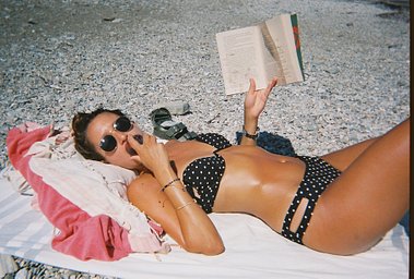 A person relaxing on a pebble beach with a book
