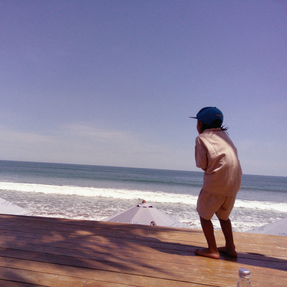 A child looking out to the ocean from a wooden deck