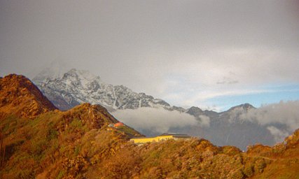 A mountain landscape with snow-covered peaks and golden foreground